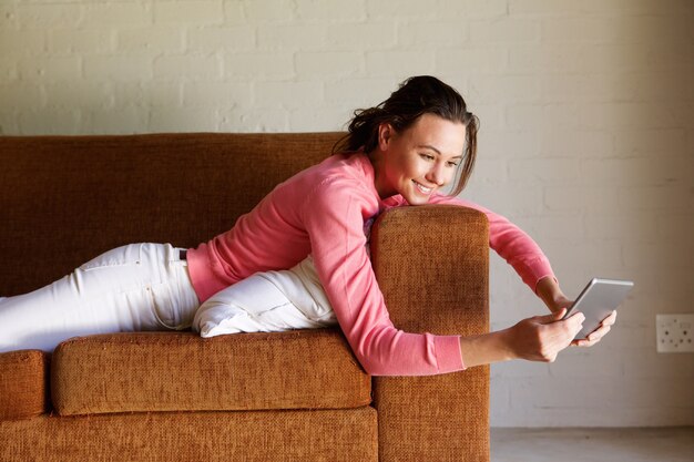 Молодая женщина на диване, используя цифровой планшет