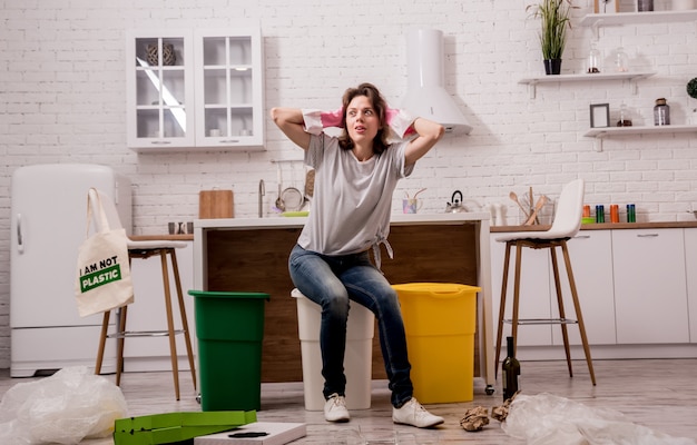 Young woman sorting garbage at the kitchen. Concept of recycling. Zero waste