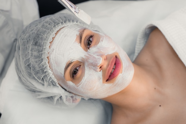 Foto giovane donna alle procedure della stazione termale che applica maschera