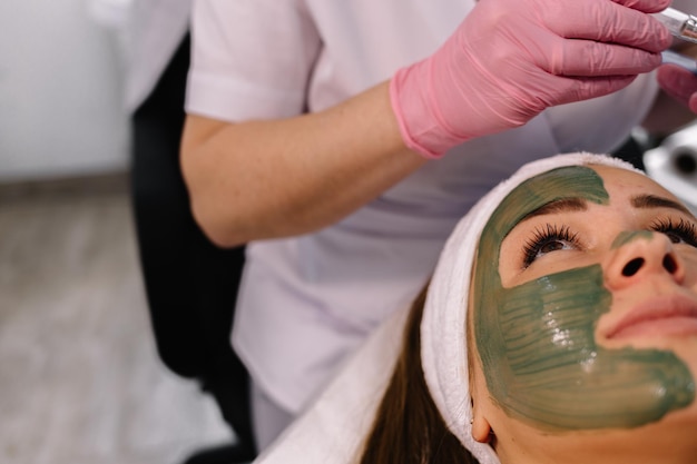 Foto giovane donna in una spa con maschera facciale alle alghe donna nel salone della stazione termale