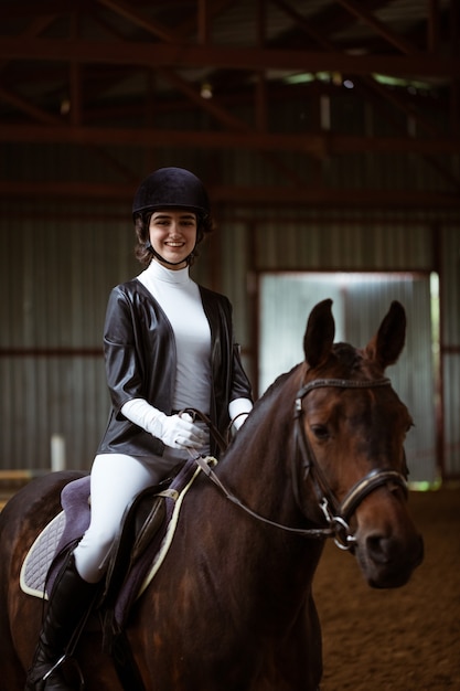 Young woman in special uniform and helmet riding horse equestrian sport