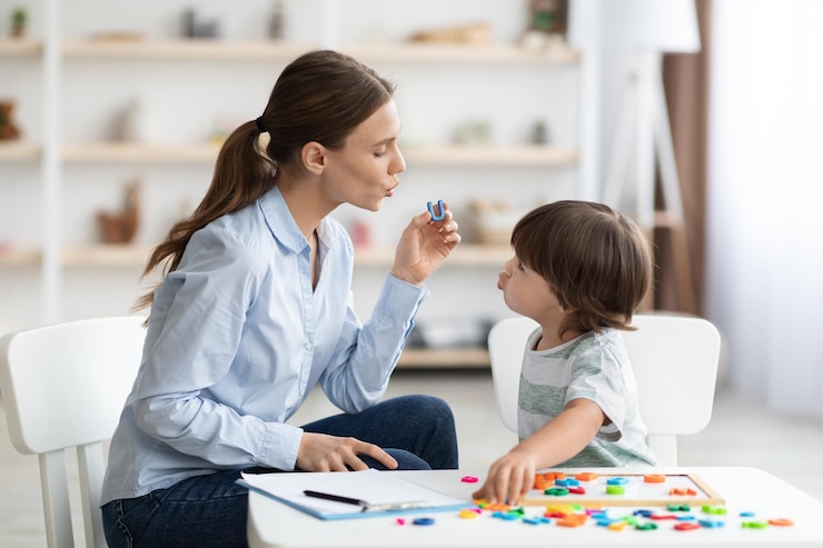 Photo young woman speech therapist teaching little boy with pronounciation deffects to say sound u during