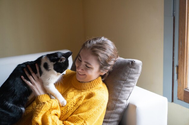 ソファで猫と時間を過ごす若い女性