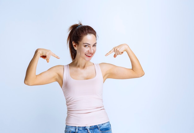 Giovane donna in camicia sportiva che indica se stessa