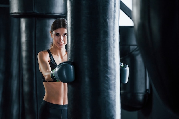 La giovane donna in abbigliamento sportivo è in palestra con una giornata di esercizio. concezione della boxe.