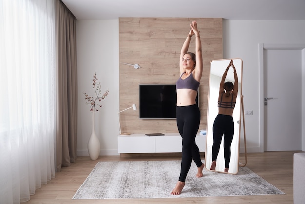 Young woman in sports clothing doing yoga while relaxing at home