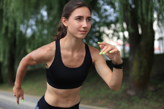 Young woman in sports clothing running while exercising outdoors.