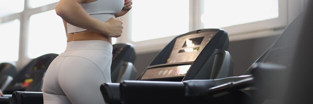 Young woman in sports uniform working out on treadmill in gym regular sports training concept