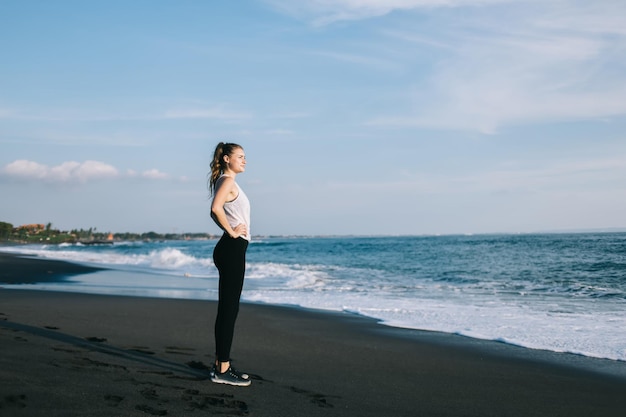 Giovane donna in abiti sportivi contro cielo e mare