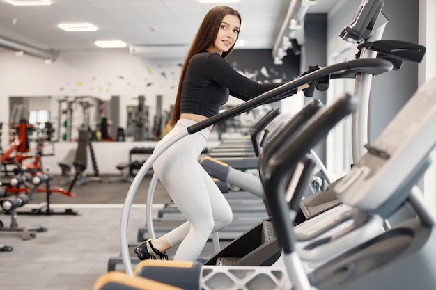 Young woman in sportswear doing excercisses with special equipment at gym