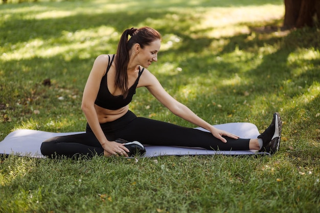 young woman in sportswear doing leg stretching in the city park