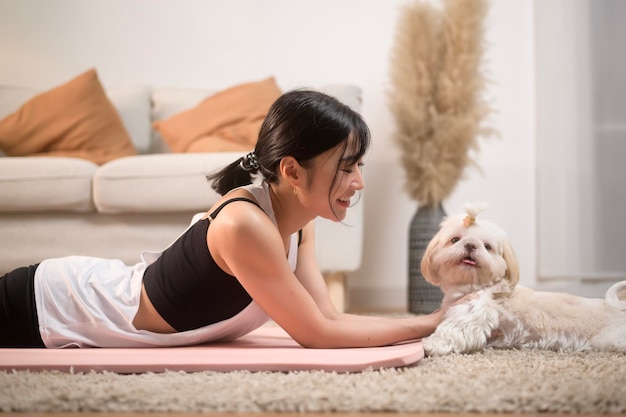 Young woman in sportswear doing meditation practice and yoga with cute dog