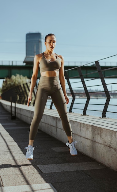 Young woman in sportswear exercising on a river promenade