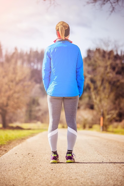 Foto giovane donna in abiti sportivi su una strada di campagna in attesa di iniziare l'allenamento