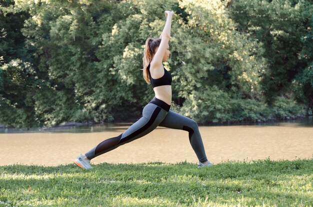 Young woman in sportswear trains in an outdoor Park