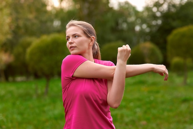 Young woman in sportswear trains in the park outdoors