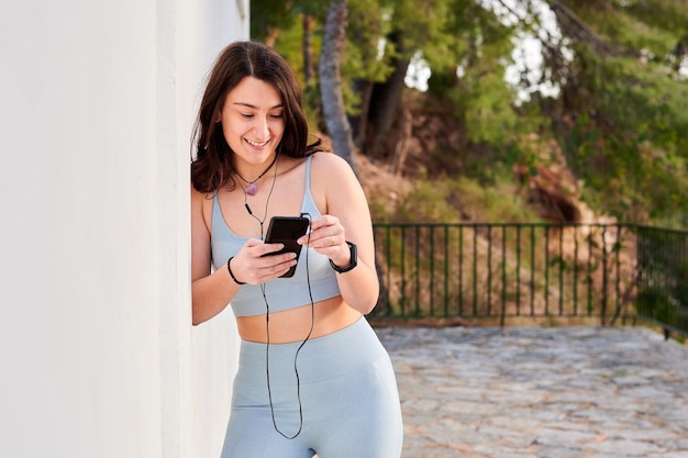 Young woman in a sportswear with a mobile listens to music