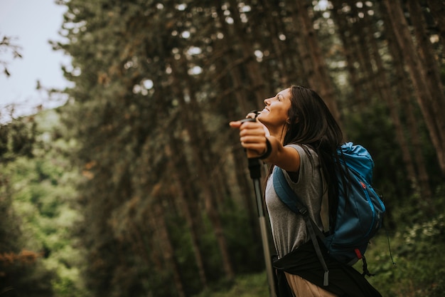 Photo young woman spreading arms and enjoying backpacking travel in the woods