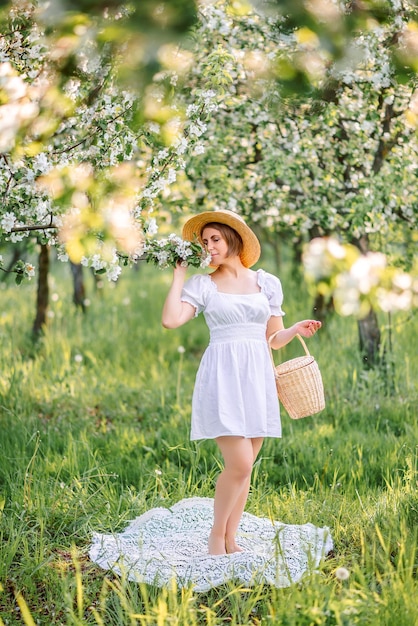 young woman in a spring garden She is wearing a white dress and a braided hat