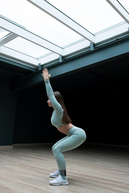 A young woman squats during a workout at home