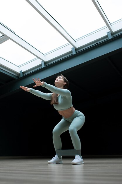 A young woman squats during a workout at home