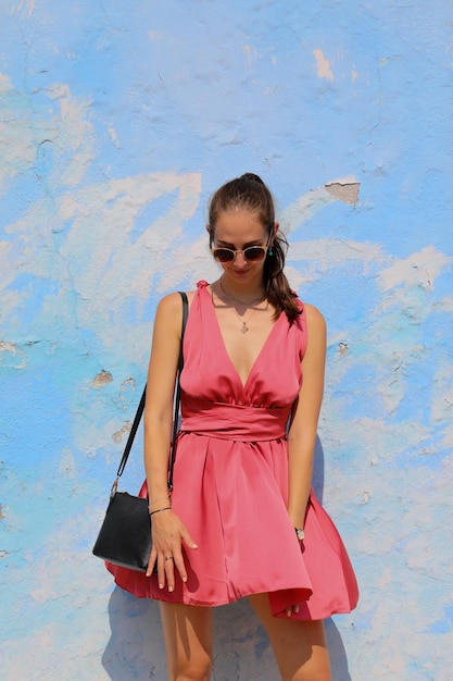 Foto giovane donna in piedi contro il muro blu