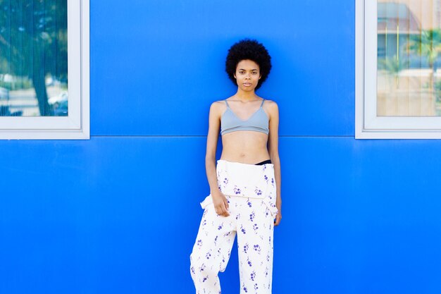 Young woman standing against blue wall