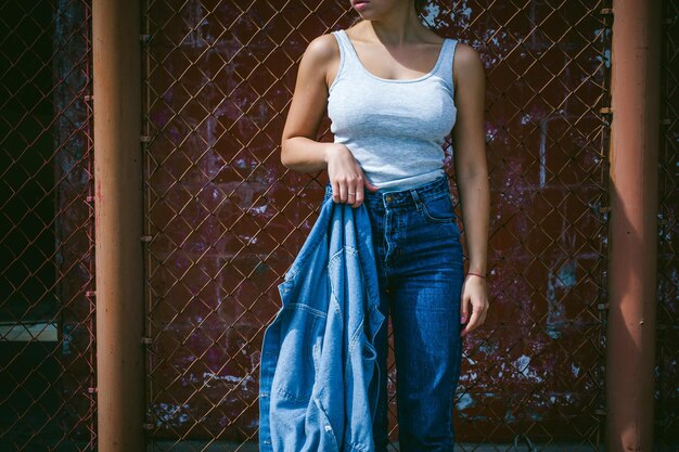 Photo young woman standing against chainlink fence