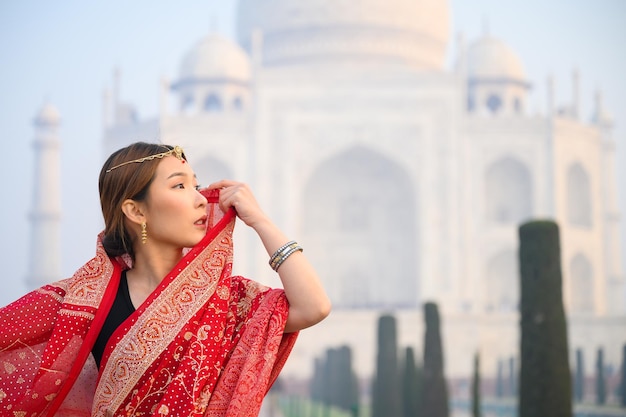 写真 インドの歴史的な建物の前に立っている若い女性
