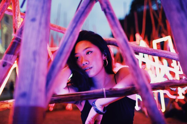 Young woman standing against illuminated lighting equipment