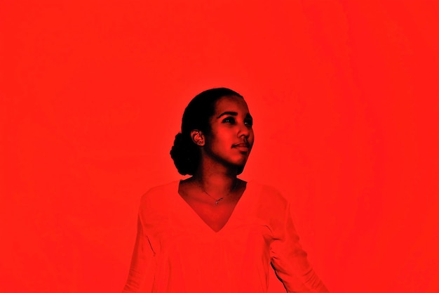 Молодая женщина стоит на красном фоне