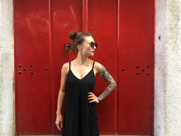 Foto giovane donna in piedi contro il muro rosso