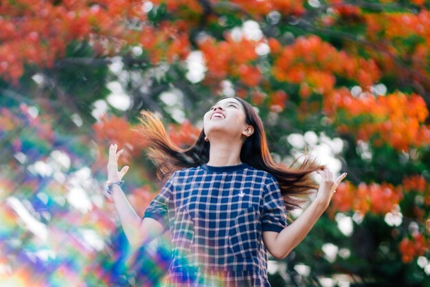 木や植物に寄りかかって立っている若い女性