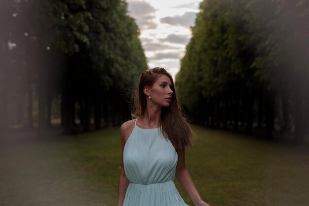 young woman standing against trees