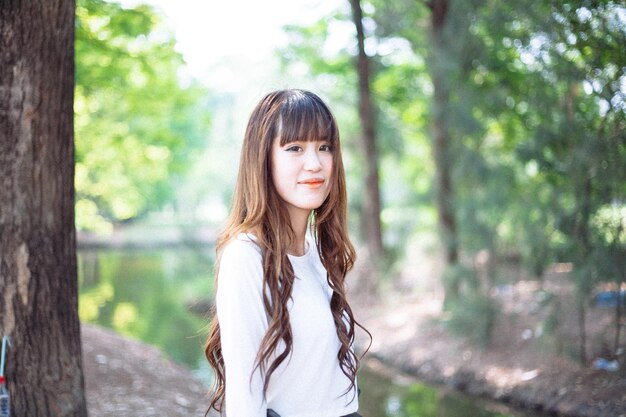 Young woman standing against trees