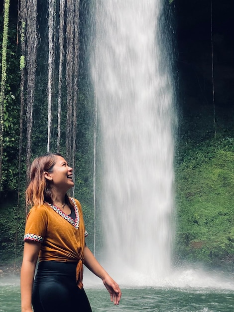 Фото Молодая женщина стоит у водопада.