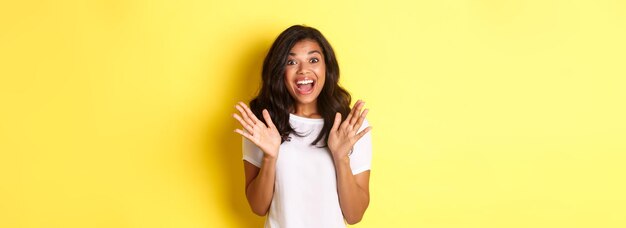 Young woman standing against yellow background