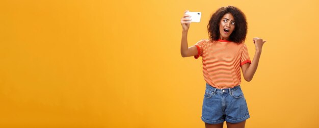 Young woman standing against yellow background