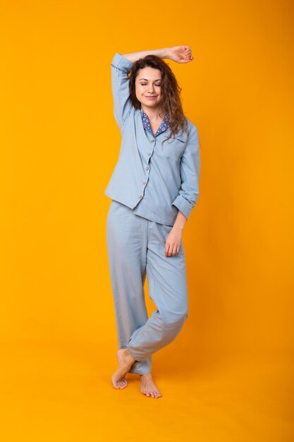 Young woman standing against yellow background