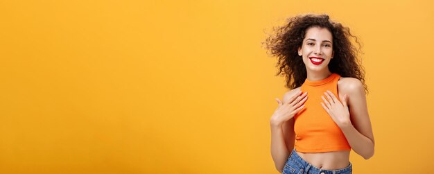 Young woman standing against yellow background