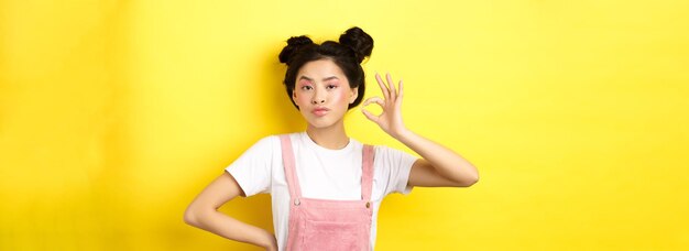 写真 黄色い背景に立っている若い女性