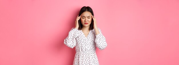 Young woman standing against yellow background