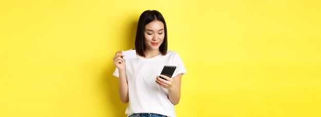 Young woman standing against yellow background