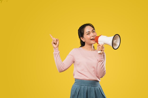 Young woman standing against yellow background