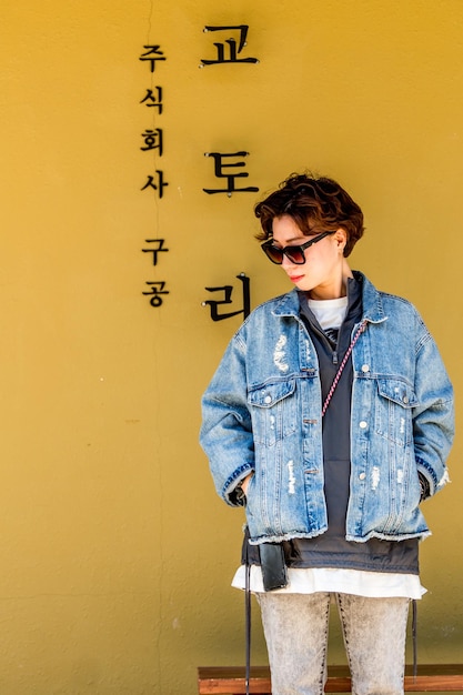 Young woman standing against yellow wall