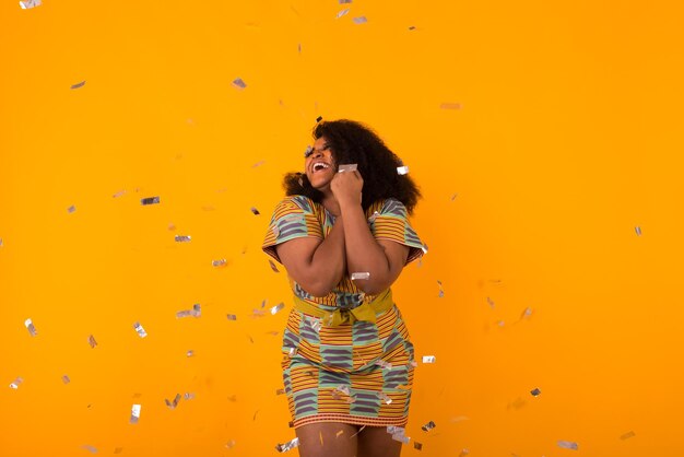 Young woman standing against yellow wall