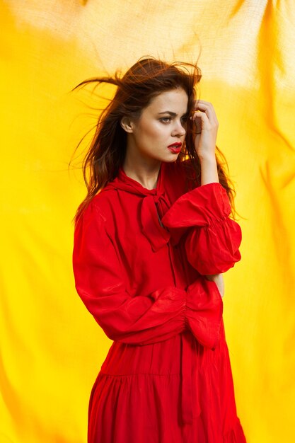 Young woman standing against yellow wall