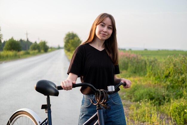 田舎で自転車で道路に一人で立っている若い女性夏の活動健康的なライフスタイル