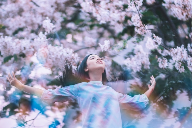 Photo young woman standing amidst flowering trees