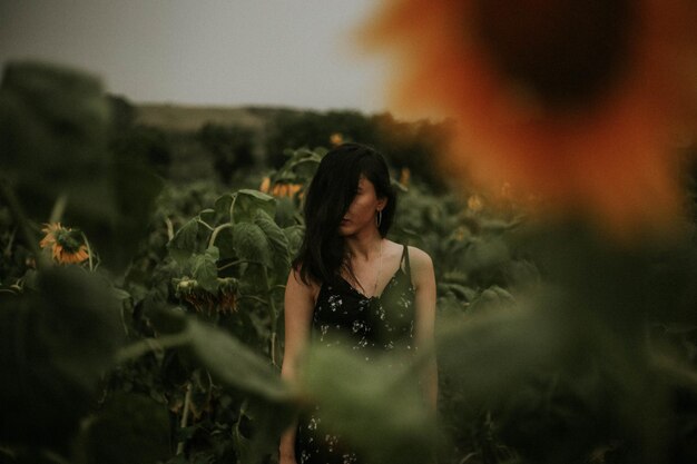 Young woman standing amidst sunflowers on field